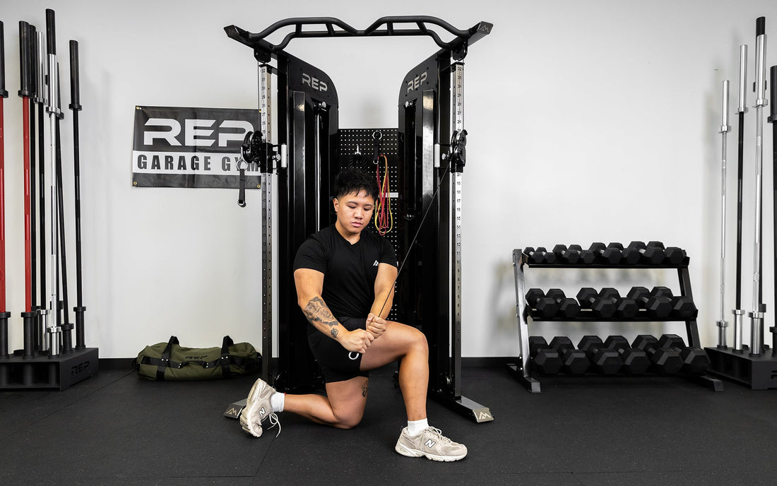 A man exercises in his home gym using a functional trainer.