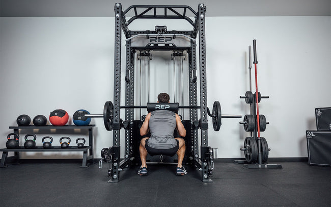 Man doing squats inside a rack with a Safety Squat Bar.